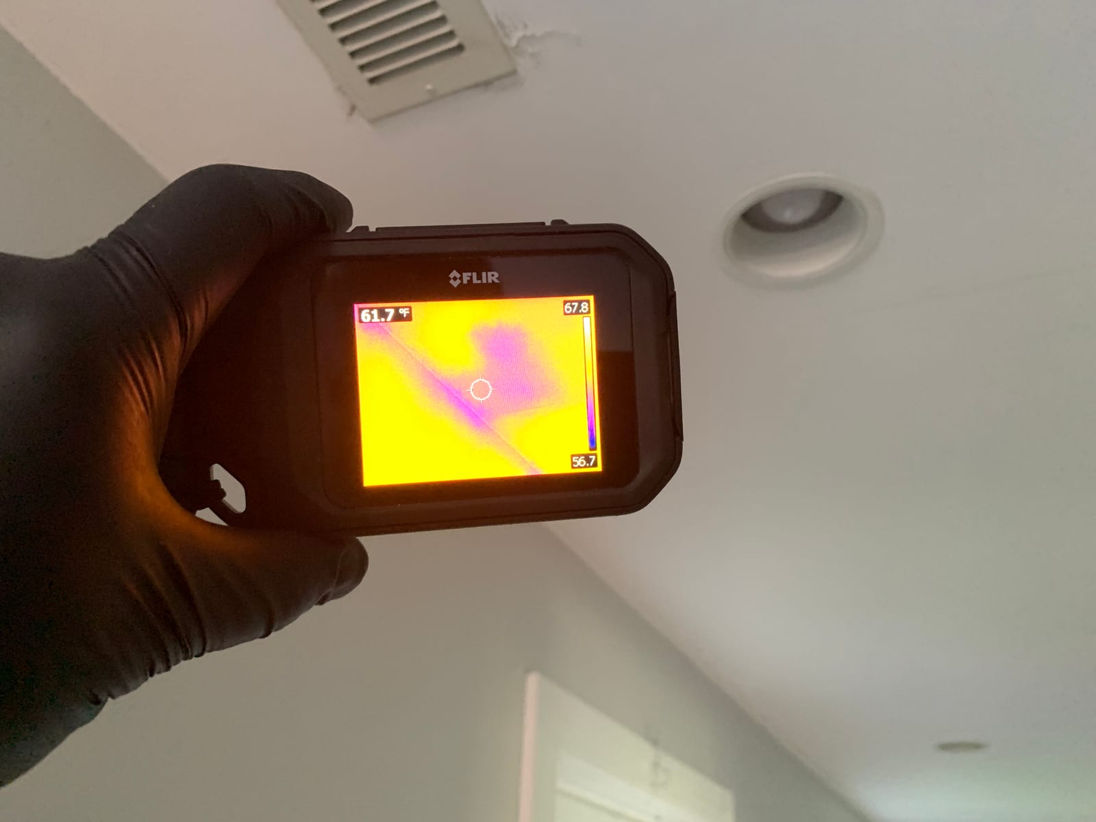 911 Storm technician using a FLIR thermal imaging camera to scan a wall for hidden moisture