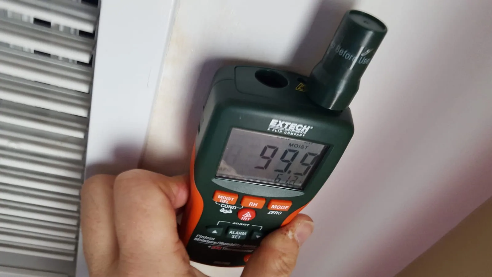 Moisture meter showing 99% reading at HVAC vent in water-damaged home